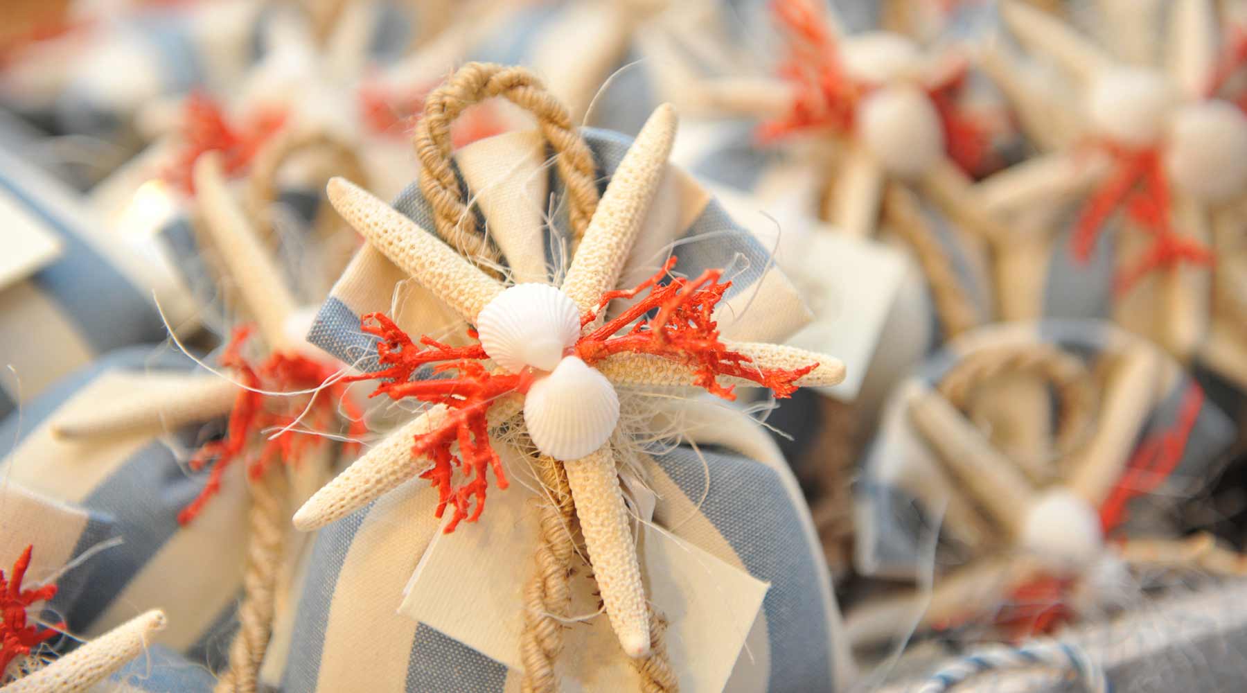 Blue and white striped wedding favor bags are tied shut with a starfish and red coral.