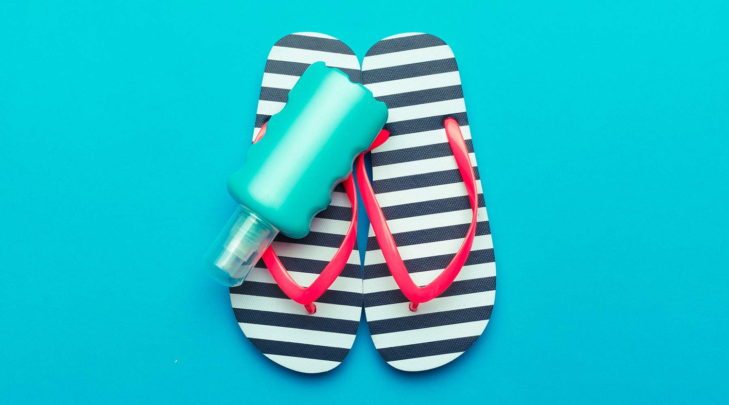 A pair of black and white stripped flip flops sit on a blue background with a bottle of decorative blue flip flop party paint on top.
